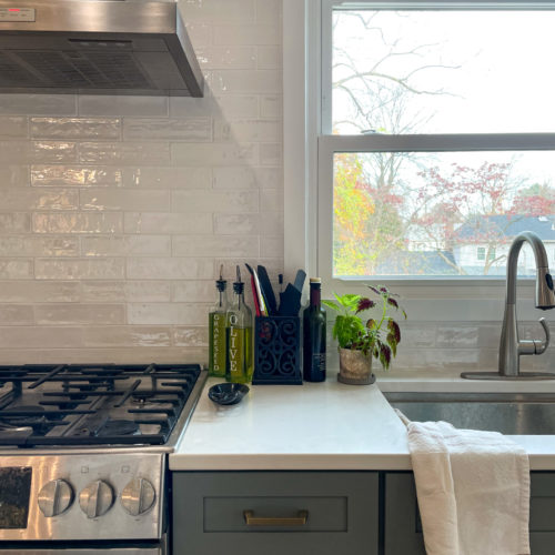 kitchen with sage cabinets, white tile backsplash and brushed silver appliances