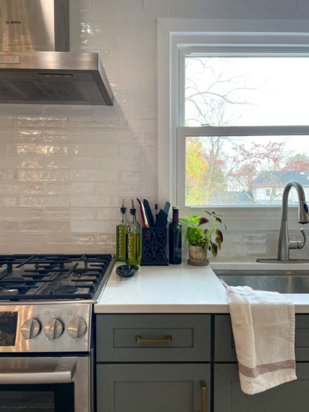 kitchen with sage cabinets, white tile backsplash and brushed silver appliances