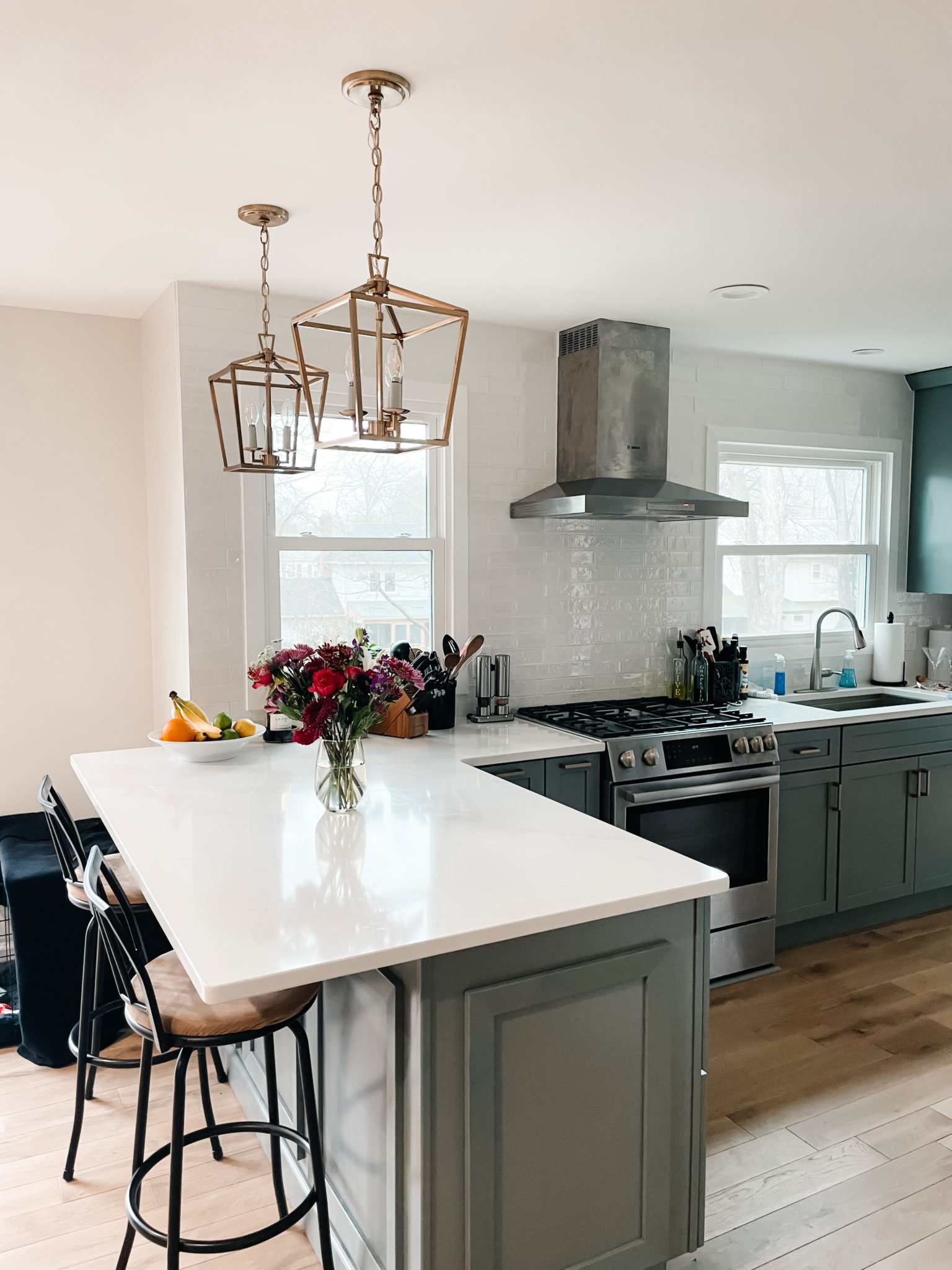 kitchen with sage cabinets, white quartz, brushed silver bosch appliances and gold hardware