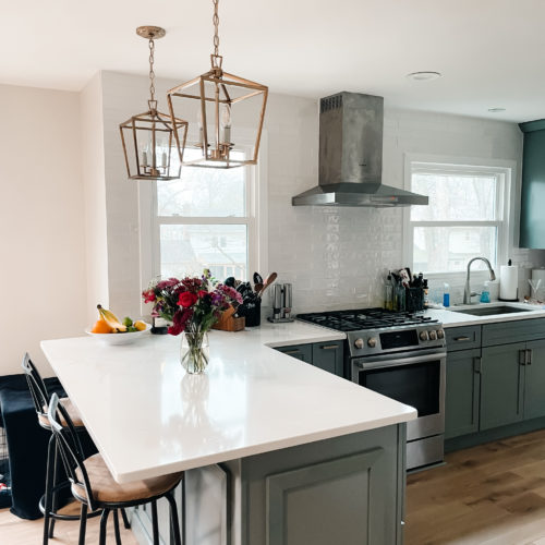 kitchen with sage cabinets, white quartz, brushed silver bosch appliances and gold hardware