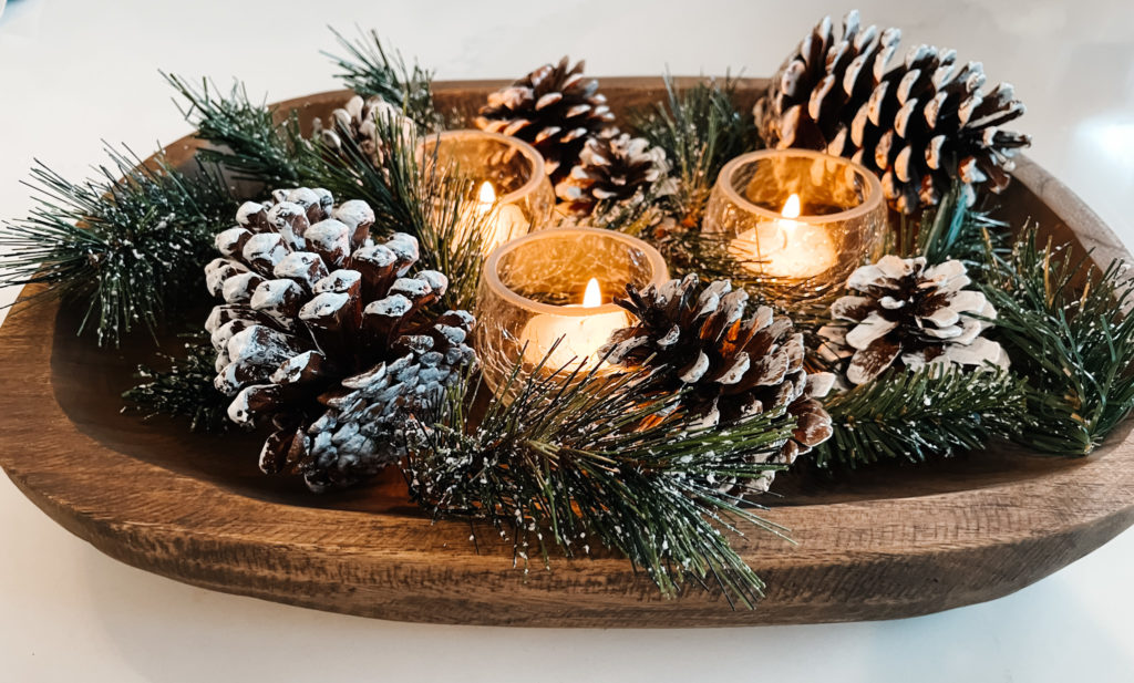 dough bowl filled with snowy pine cones, evergreen and candles