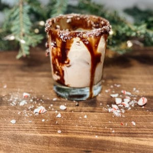 Glass of peppermint white russian cocktail with a chocolate and candy cane rim