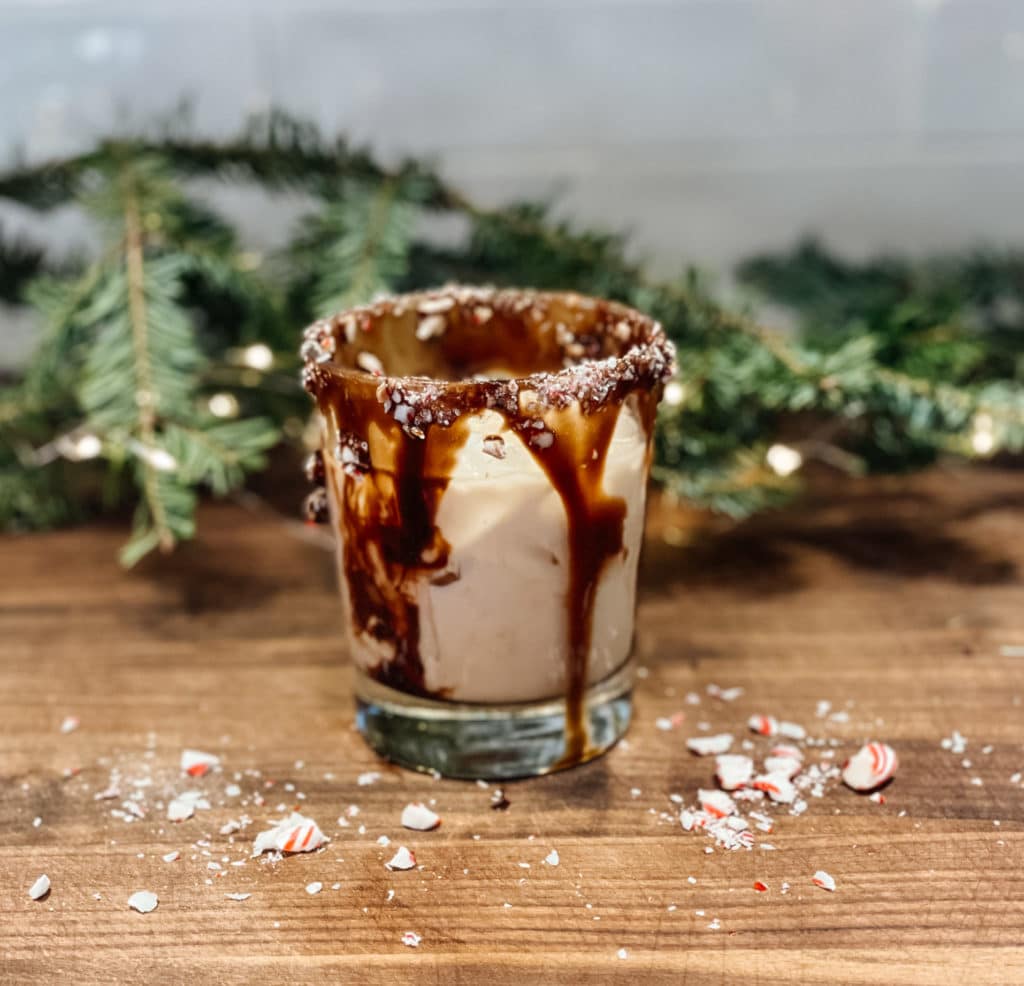 Glass of peppermint white russian cocktail with a chocolate and candy cane rim