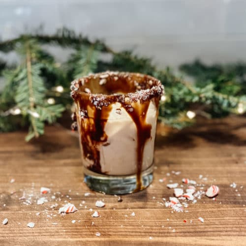Glass of peppermint white russian cocktail with a chocolate and candy cane rim