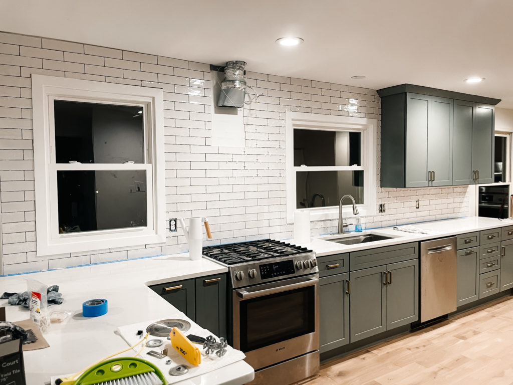 white tile being installed in a green kitchen